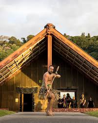 Māori wharenui with people entering the meeting house